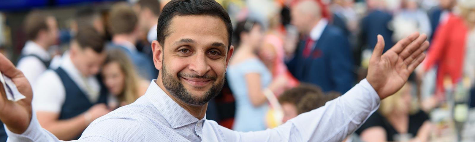 A man holds his hands up and smiles at the camera