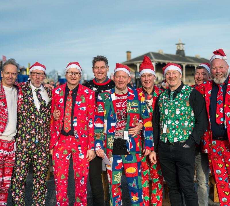 A group of men dressed in festive outfits at the races 