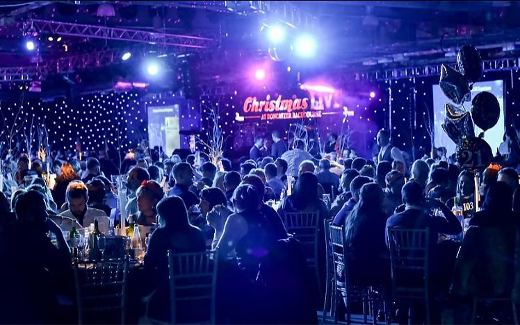 A room full of people sit for food at their christmas party