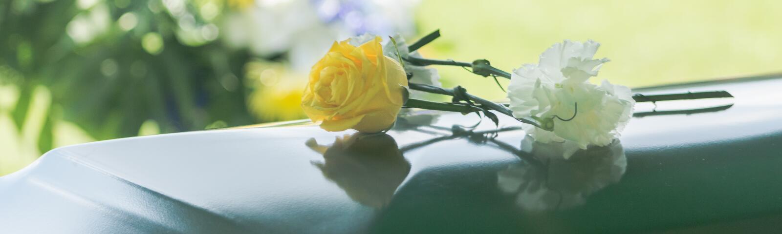 A yellow and White flower sit ontop of a casket