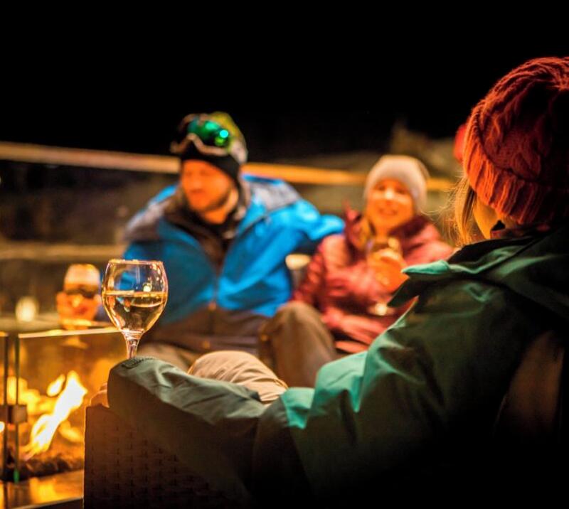 People are drinking wine around a firepit  