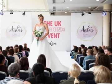 A woman in a wedding dress stood on stage at a wedding fair 