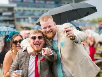 Two race goers in suits at Doncaster point to the camera