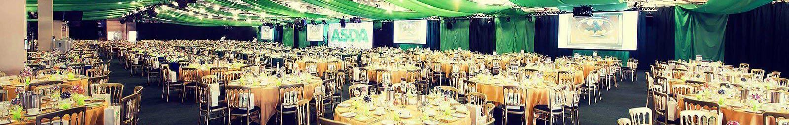 A large convention room filled with clothed tables ready for a meal