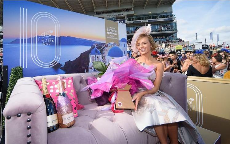 The winner of the ladys day poses with flowers and champagne