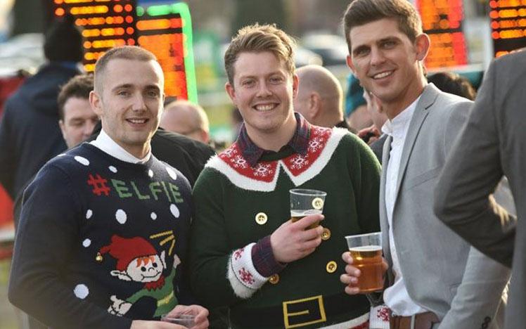 Couple of gentlemen wearing christmas jumpers while at the races.