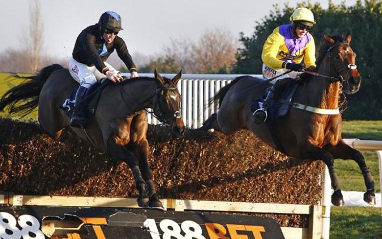 Two jockeys on horses jumping over a hurdle.