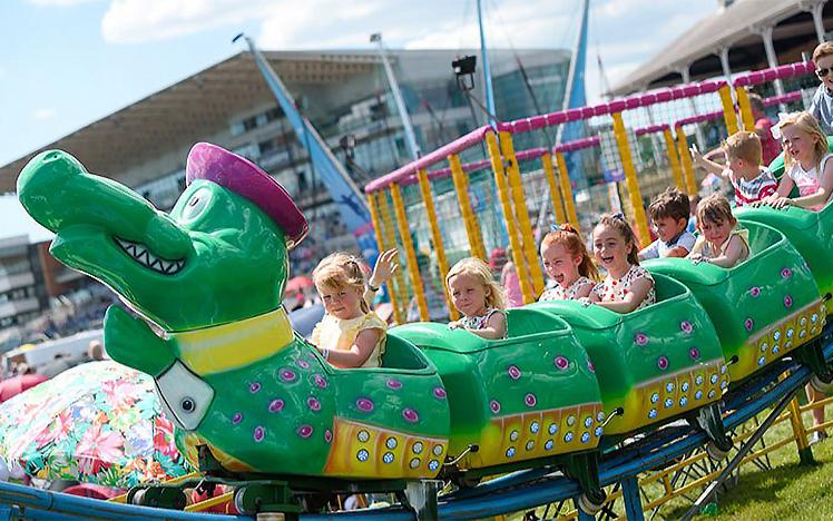 Children scream on the back of a rollarcoaster in the shape of a caterpillar