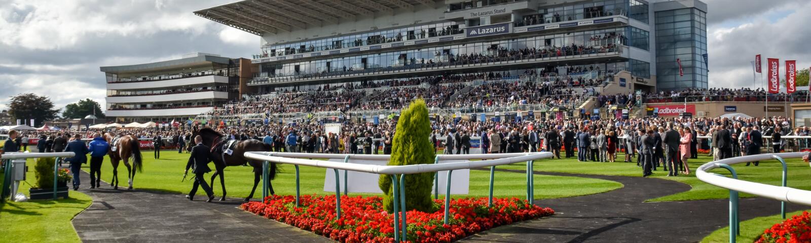 The parade ring at Doncaster with the crowds in the enclosures and stands behind