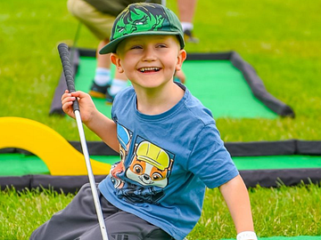 Child smiling holding a golf putter