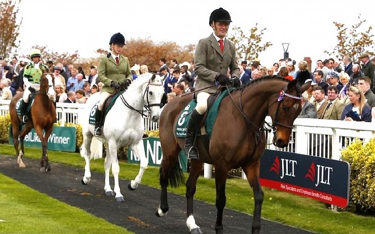 Two jokeys parade their horses around the parade ring